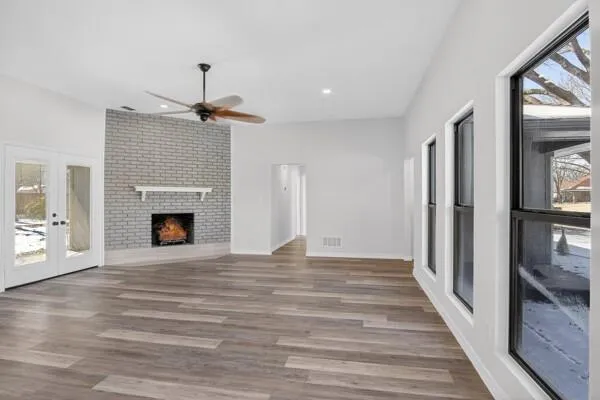 a view of an empty room with wooden floor fireplace and a window