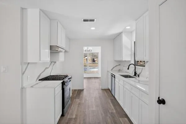 a kitchen with granite countertop a sink stove and cabinets