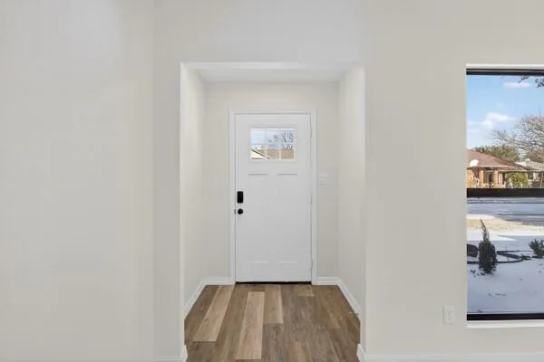 a view of a hallway with wooden floor and a bathroom