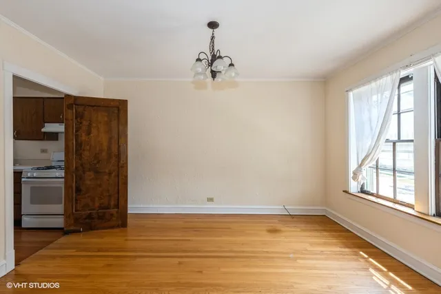 a view of empty room with wooden floor and kitchen
