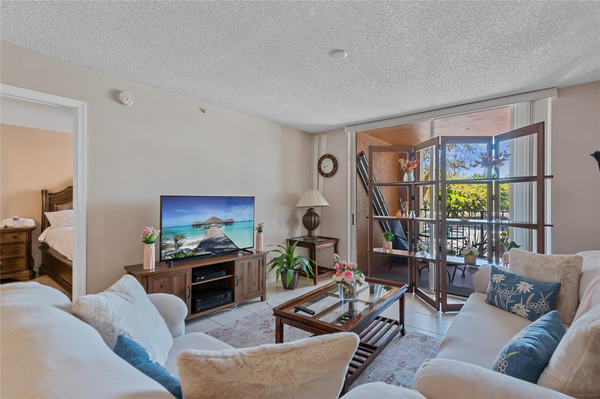 2133 Renaissance Boulevard, Unit 205 Miramar, FL 33025 - Photo 2 of 24 a living room with furniture a flat screen tv and a floor to ceiling window