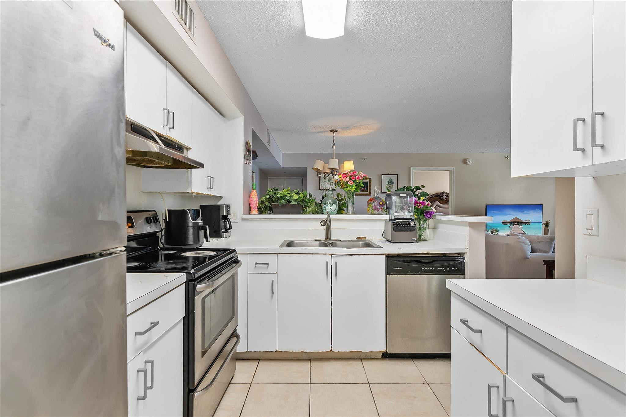 2133 Renaissance Boulevard, Unit 205 Miramar, FL 33025 - Photo 6 of 24 a kitchen with a sink dishwasher stove and white cabinets
