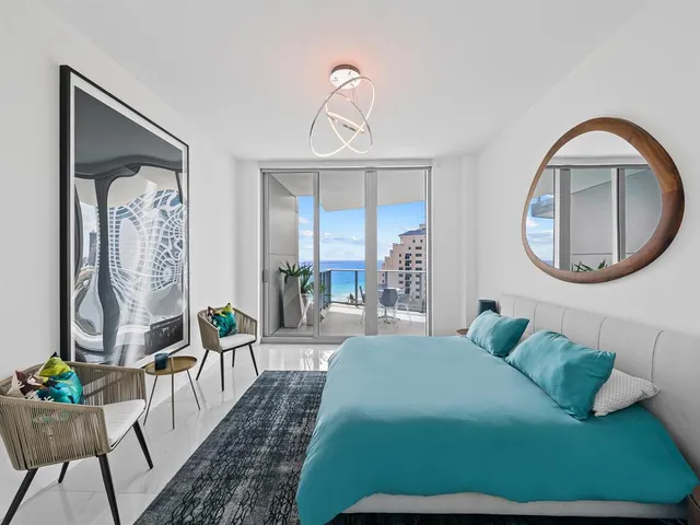 a bedroom with a bed mirror and painting on the wall