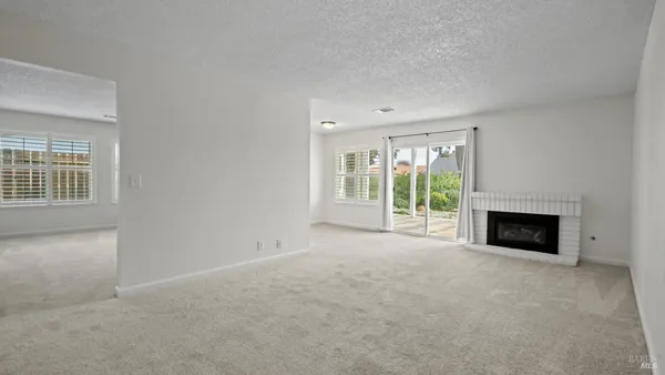 a view of an empty room with a fireplace and a window