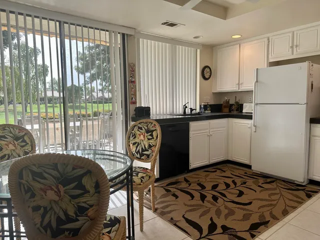 a kitchen with stainless steel appliances a refrigerator a sink and white cabinets