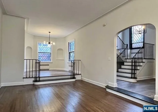 an empty room with windows fireplace and wooden floor