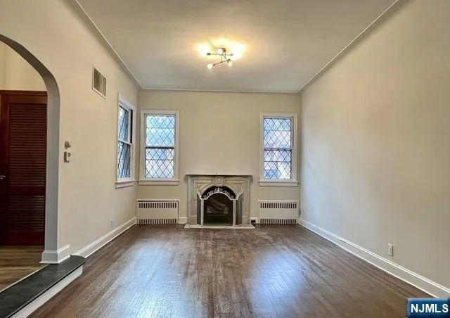 an empty room with windows a fireplace and wooden floor