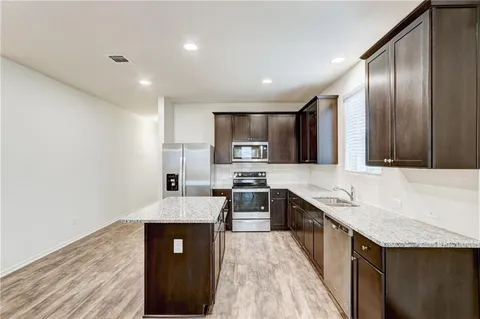 a large kitchen with granite countertop a sink counter space and stainless steel appliances