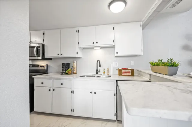 a kitchen with stainless steel appliances granite countertop white cabinets sink and a granite counter top