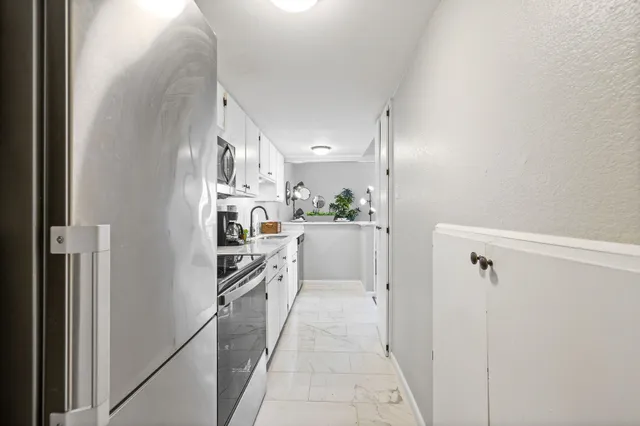 a kitchen with kitchen island a counter top space a refrigerator and cabinets
