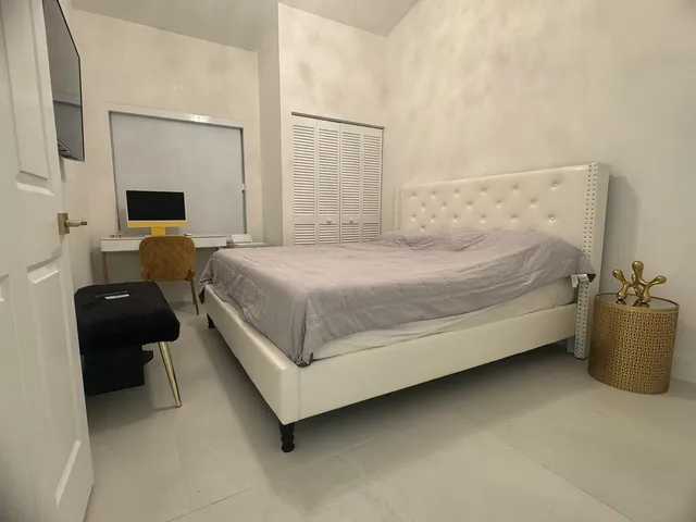 a bed sitting in a bedroom and table chair
