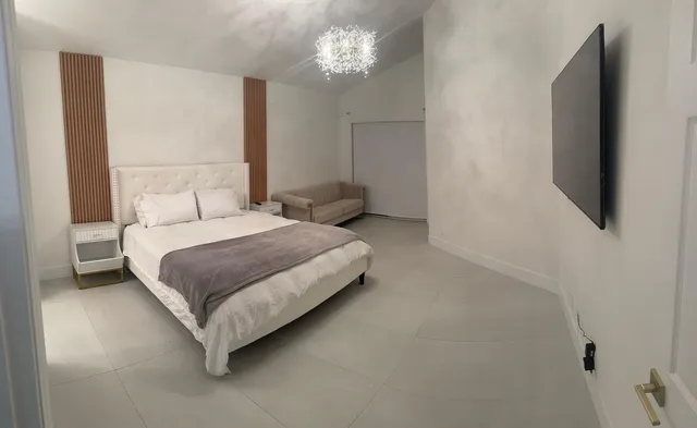 a bedroom with a bed flat screen tv and a chandelier