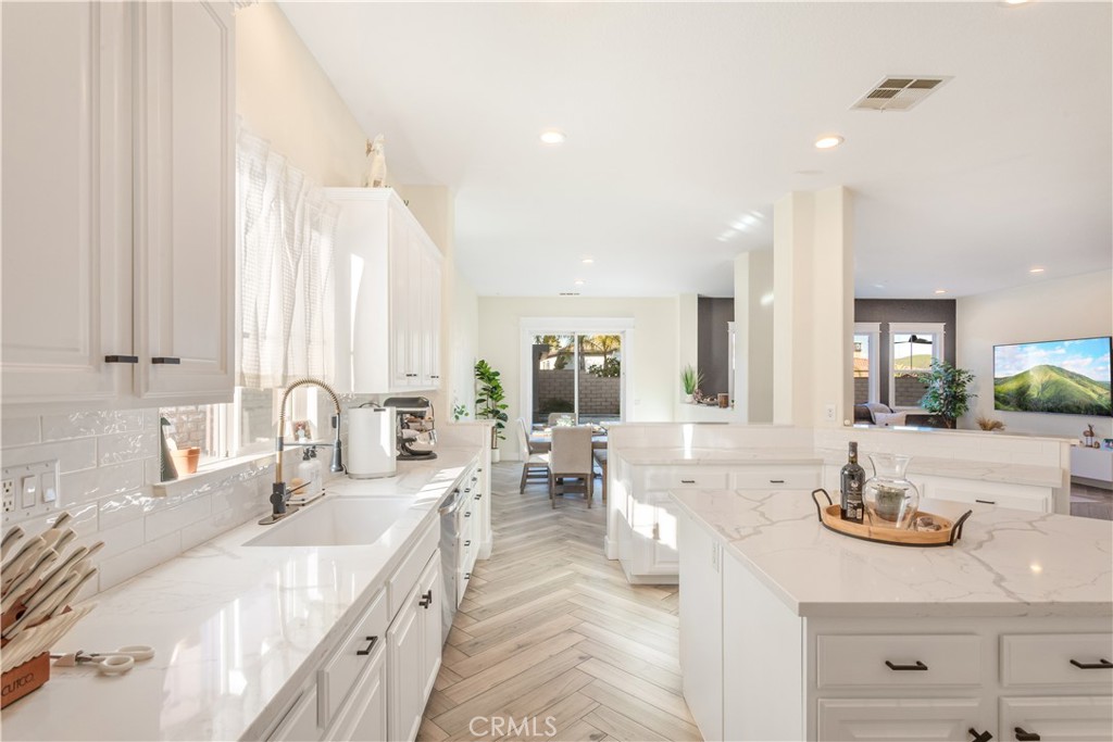 8824 Soothing Court Corona, CA 92883 - Photo 17 of 50 a kitchen with sink stove and white cabinets with wooden floor