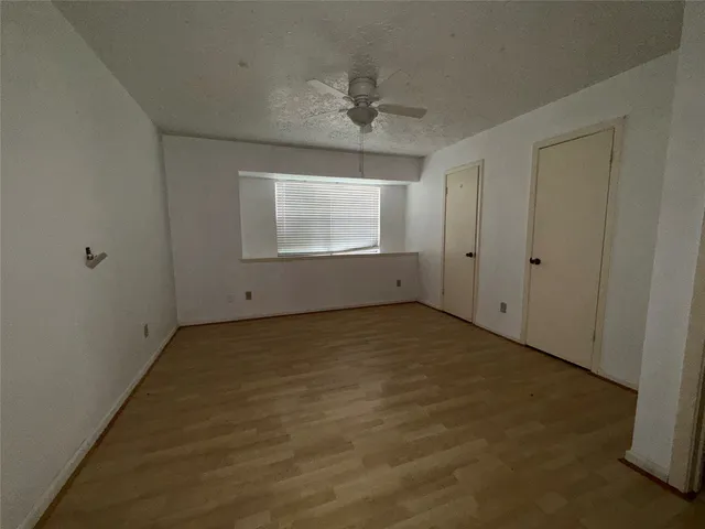 an empty room with a ceiling fan and window