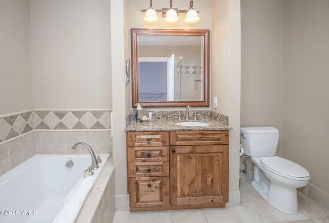 a bathroom with a granite countertop bathtub sink vanity and mirror
