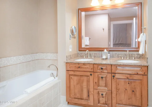 a bathroom with a granite countertop bathtub sink and mirror