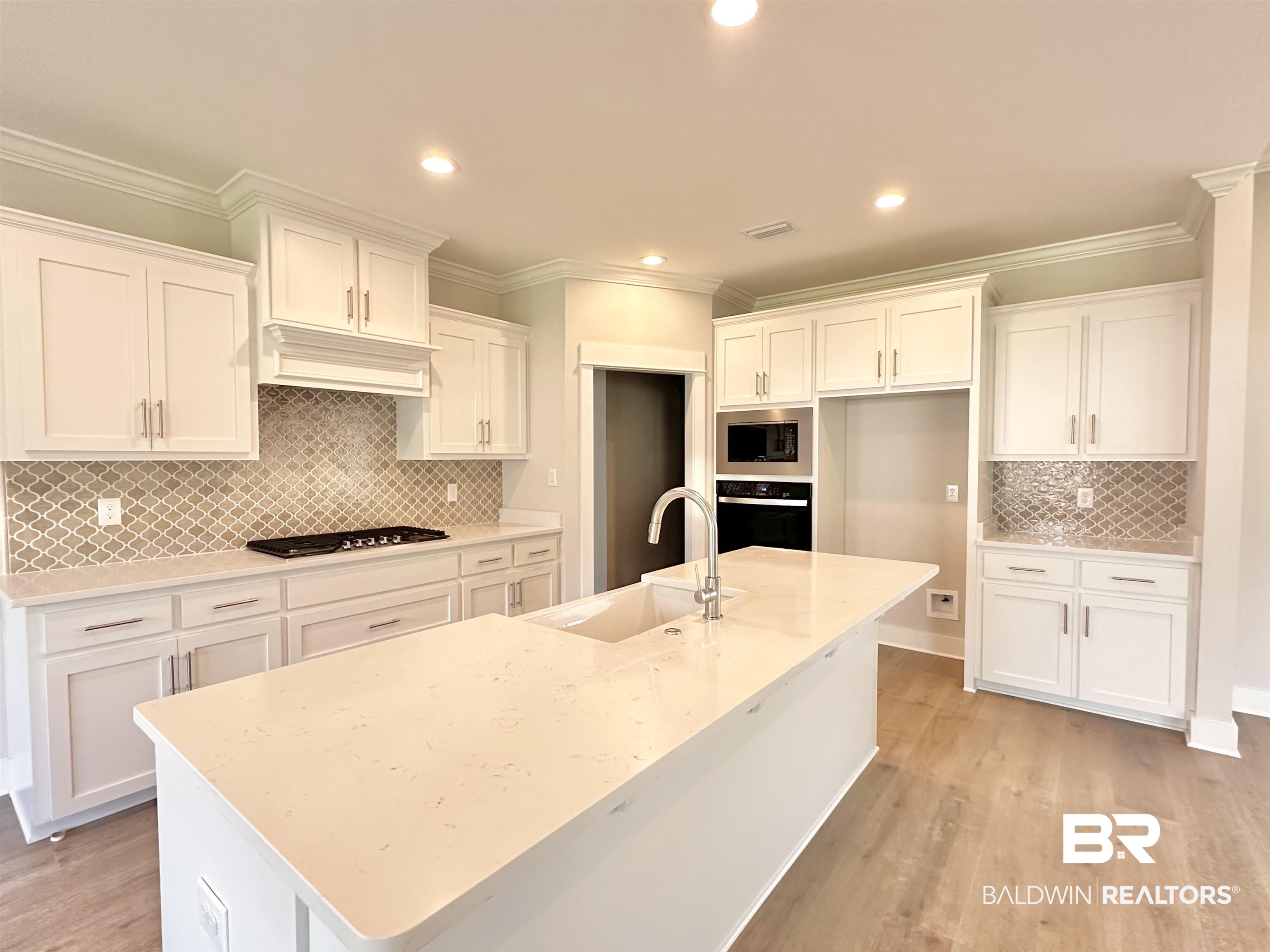 634 Kitfox Avenue Fairhope, AL 36532 - Photo 4 of 33 Kitchen with decorative backsplash, an island with sink, appliances with stainless steel finishes, light hardwood / wood-style floors, and sink