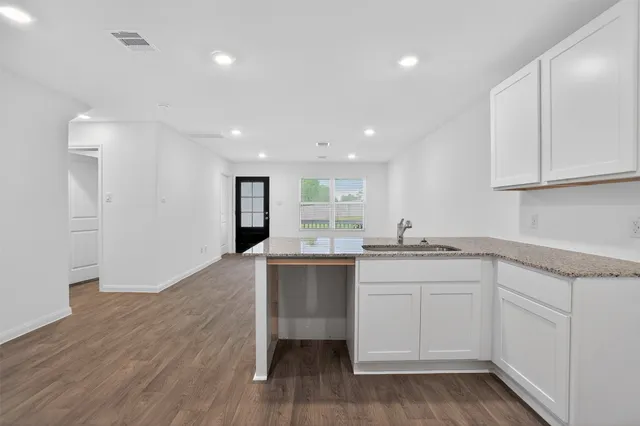 a kitchen with a sink cabinets and wooden floor