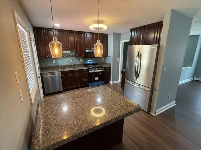 a kitchen with granite countertop a stove refrigerator and microwave