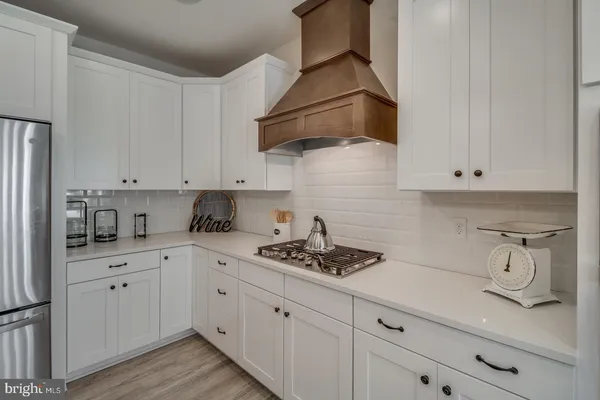 a open kitchen with stainless steel appliances granite countertop a stove a kitchen island a dining table and chairs with wooden floor