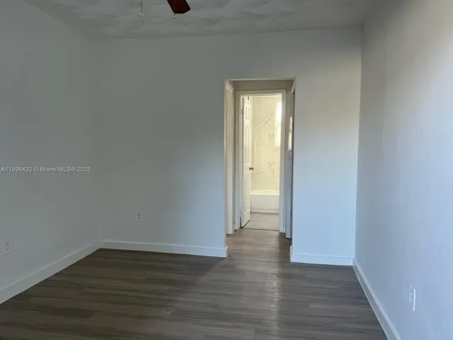 a view of an empty room with wooden floor and closet