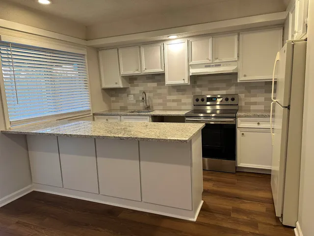 a kitchen with stainless steel appliances granite countertop a sink a stove a refrigerator and cabinets