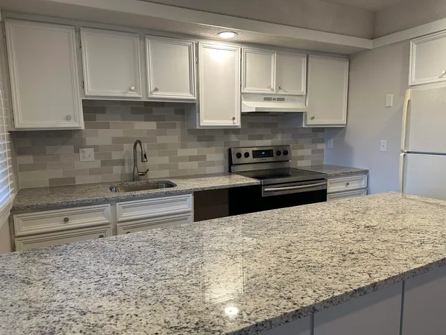 a kitchen with granite countertop a sink a stove and a refrigerator