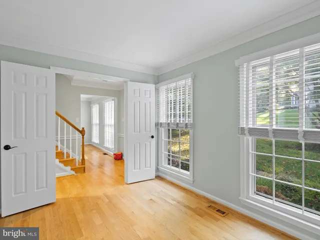 a view of an empty room with chandelier fan and wooden floor