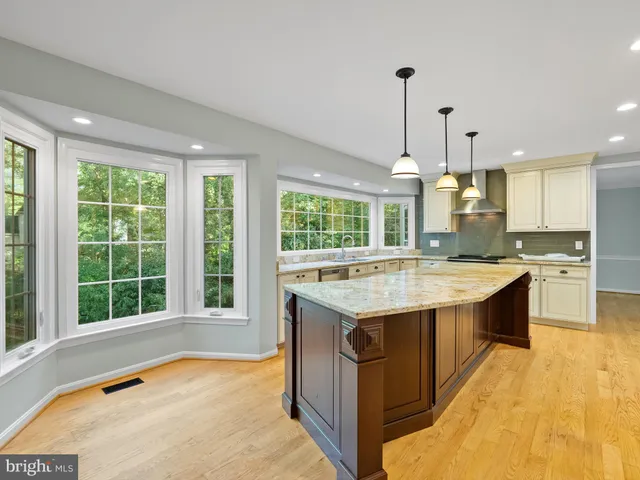 a large kitchen with kitchen island a sink stainless steel appliances and a chandelier