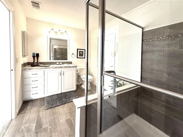 a kitchen with stainless steel appliances kitchen island granite countertop a stove a sink and white cabinets with wooden floor