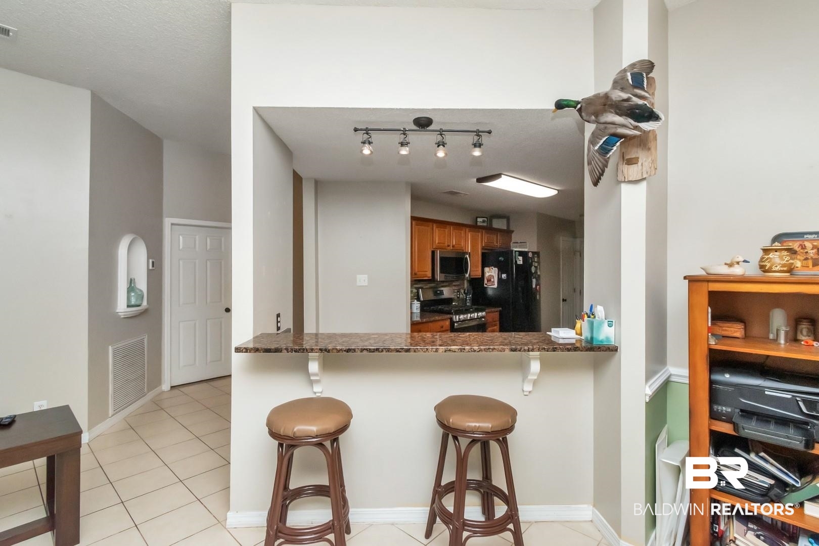 29221 Canterbury Road Daphne, AL 36526 - Photo 10 of 17 Kitchen with black appliances, dark stone countertops, light tile patterned flooring, kitchen peninsula, and a breakfast bar area