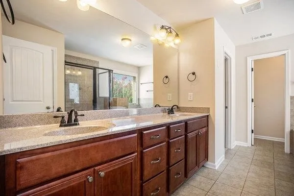 a bathroom with a double vanity sink and mirror with shower