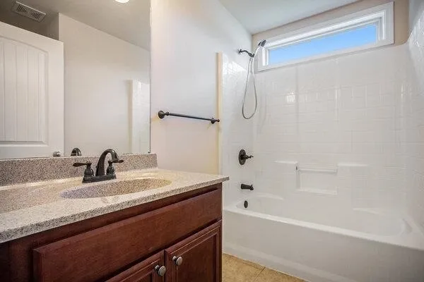a bathroom with a granite countertop sink a mirror and a bathtub