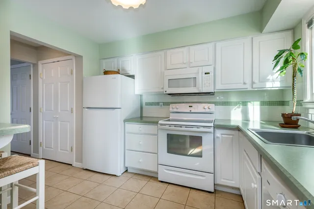 a kitchen with white cabinets and white appliances