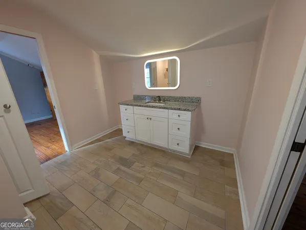 a room with granite countertop a sink and a mirror