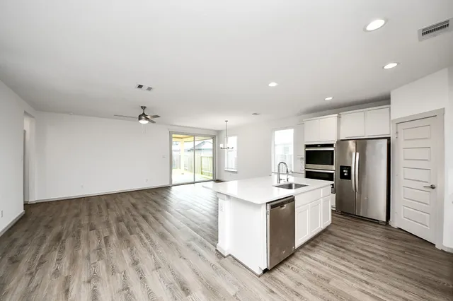 a kitchen with stainless steel appliances a white stove top oven a refrigerator cabinets and wooden floor