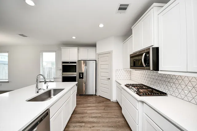 a large white kitchen with stainless steel appliances granite countertop a sink stove oven and refrigerator