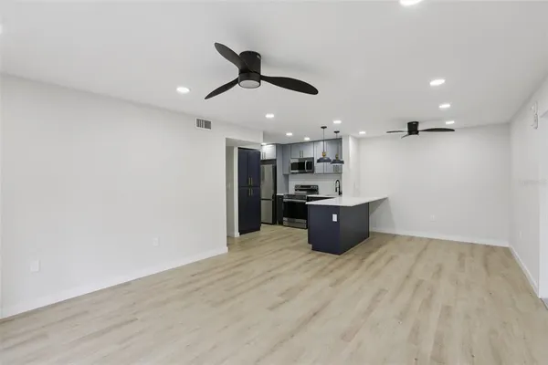 a kitchen with stainless steel appliances a stove top oven a sink a refrigerator and white cabinets