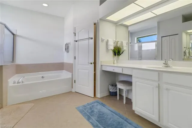 a en suite bathroom with a granite countertop tub sink and a mirror