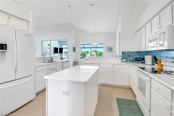 a kitchen with white cabinets appliances and a window