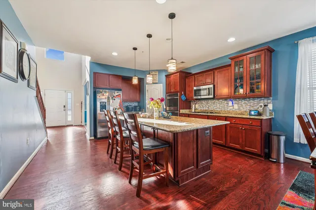 a kitchen with stainless steel appliances granite countertop a stove a refrigerator a kitchen island a sink a table and chairs