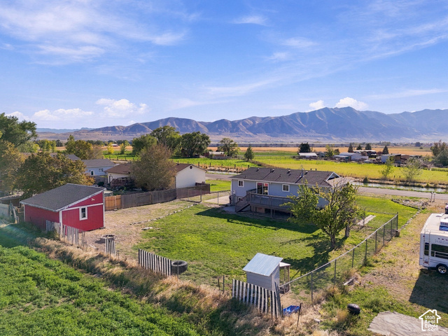 224 Canal Bank Road Garland, UT 84312 - Photo 4 of 21 Expansive property featuring a detached red shed, chain-link fencing, a two-story residence with a deck, and distant mountain scenery