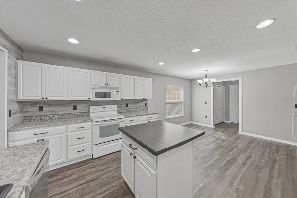 a open kitchen with white cabinets and white appliances