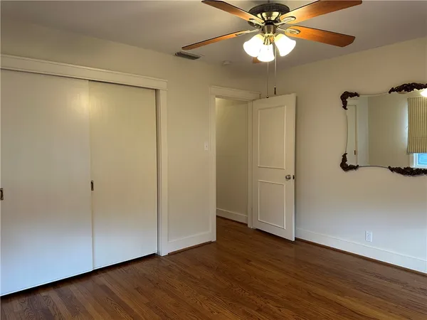 a view of a room with wooden floor a ceiling fan and window