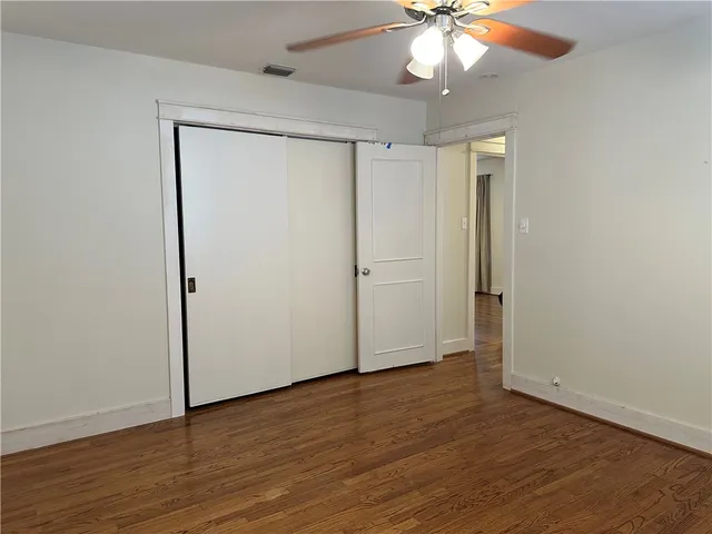 an empty room with wooden floor and a ceiling fan