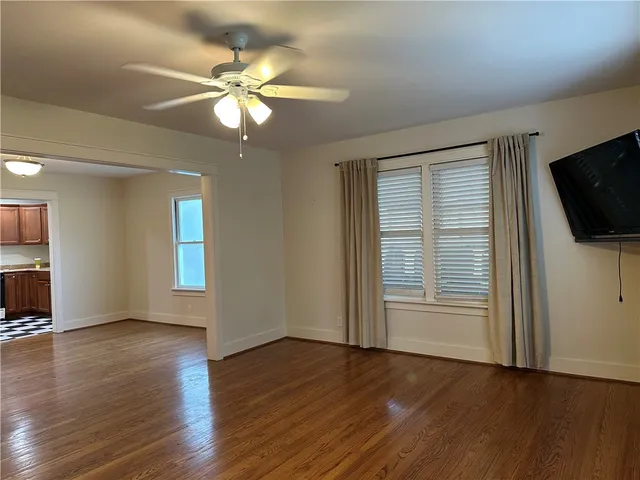 a view of an empty room with wooden floor and a window