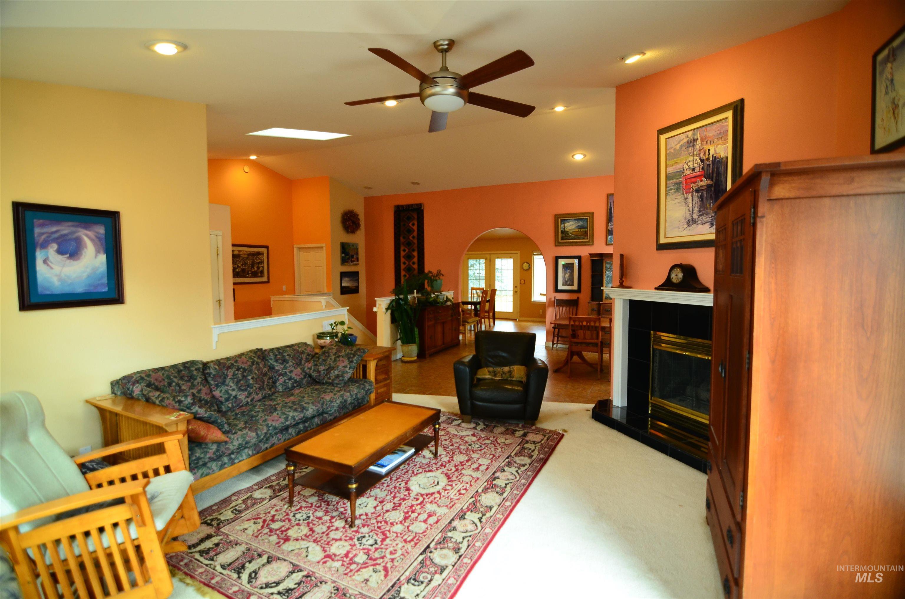 690 Granite Way Boise, ID 83712 - Photo 14 of 30 Living room featuring arched walkways, a tiled fireplace, recessed lighting, vaulted ceiling, and a ceiling fan