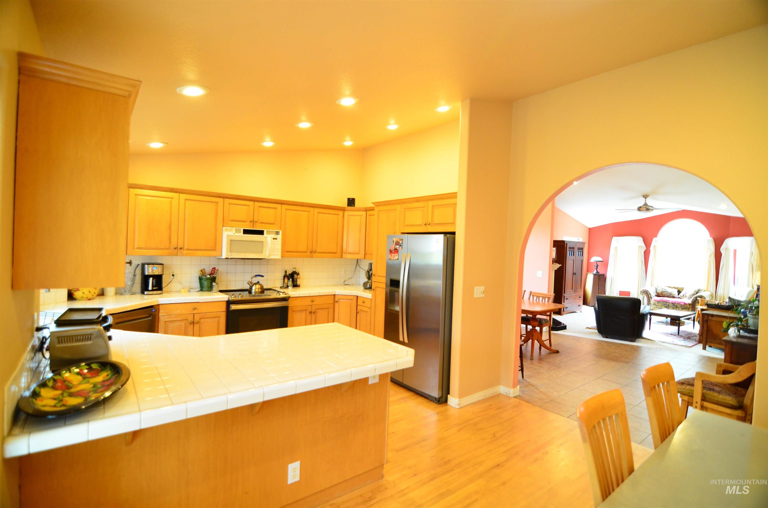 690 Granite Way Boise, ID 83712 - Photo 7 of 30 Kitchen featuring tile counters, a peninsula, vaulted ceiling, arched walkways, and stainless steel appliances