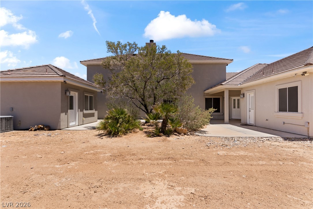 575 Gann Avenue Logandale, NV 89021 - Photo 58 of 75 A spacious desert home featuring a tiled roof and stucco exterior, set against a bright, clear sky.