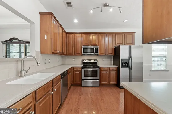 a kitchen with a sink a refrigerator and a stove top oven with wooden floor